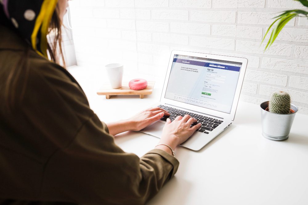 woman login into facebook website on laptop | Facebook Ads: Tipos de Campañas