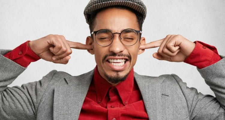 Funny bearded guy wears old fashionable clothes, plugs ears as ignores wife`s remarks and orders, fe